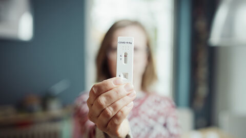 Frau zu Hause mit einem Corona-Selbsttest in der Hand. Frau zu Hause mit einem Corona-Selbsttest in der Hand.