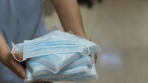 Medizinische Masken Eine Person hält eingepackte Stapel von medizinischen Masken