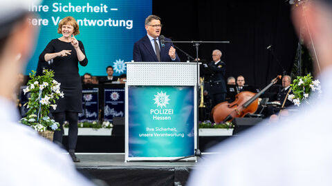 Ministerpräsident Boris Rhein steht auf einer Bühne und spricht. 