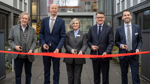v.l.n.r.: Eigentümer Andrzej Lyson, Bildungsminister Armin Schwarz, Evelin Spyra, Leiterin des Staatlichen Schulamts, Ministerpräsident Boris Rhein, Carsten Mergenthaler von der Lehrkräfteakademie) Fünf Personen stehen vor einem Gebäude mit jeweils einer Schere in der Hand. Vor ihnen ein rotes Band welches sie gemeinsam durchschneiden.