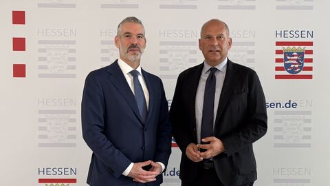 Von links nach rechts: Daniel Neumann und Roman Poseck stehen vor einem Plakat mit dem Logo des Innenministeriums.