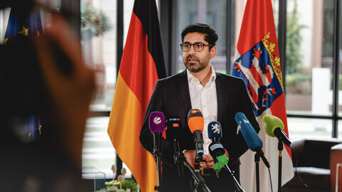 Wirtschaftsminister und stellvertretender Ministerpräsident Kaweh Mansoori im Interview vor dem Rüstungsgipfel. Wirtschaftsminister Mansoori steht vor Mikrofonen in einer Interviewsituation.