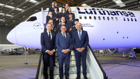 Taufe der neuen Lufthansa-Maschine Boeing 787-9 Dreamliner Maschine  Mehrere Personen stehen vor dem Eingang eines Flugzeugs und lächeln.