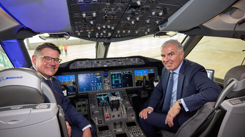 Ministerpräsident Boris Rhein und Lufthansa-Vorstandsvorsitzender Carsten Spohr im Cockpit der Lufthansa-Maschine „Frankfurt am Main“. Zwei Männer in Anzügen sitzen vorne im Cockpit des Flugzeugs.