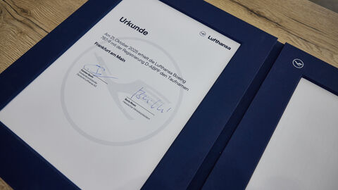 Die unterschriebene Taufurkunde der „Frankfurt am Main“. Eine unterschriebene Urkunde, die auf einem Holztisch liegt.