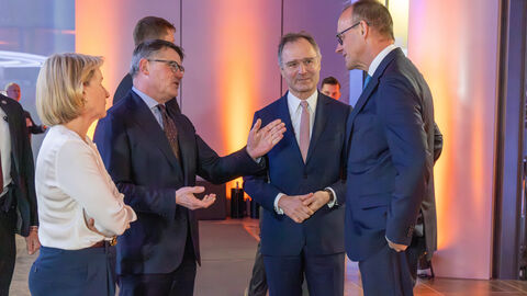 Mann im Anzug im Gespräch mit zwei Männern und einer Frau.