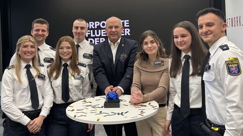 Innenminister Roman Poseck mit den neuen Corporate Influencern. Innenminister Poseck steht mit sechs Polizistinnen und Polizisten in Ausbildung um einen Stehtisch herum.